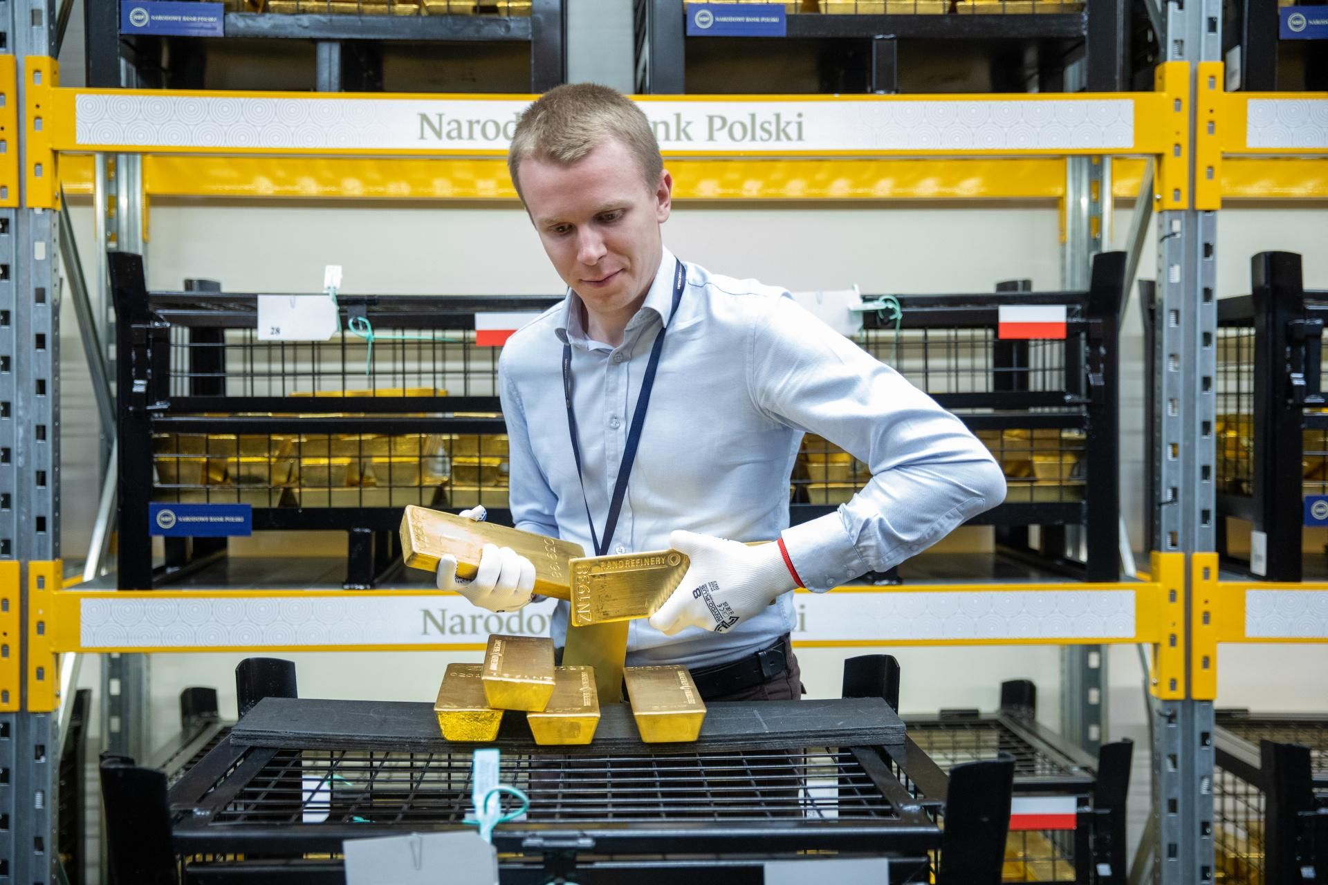 Antoni Łaszewski podnosi dwie sztaby złota ważące po 12,5 kg podczas wizyty w skarbcu NBP